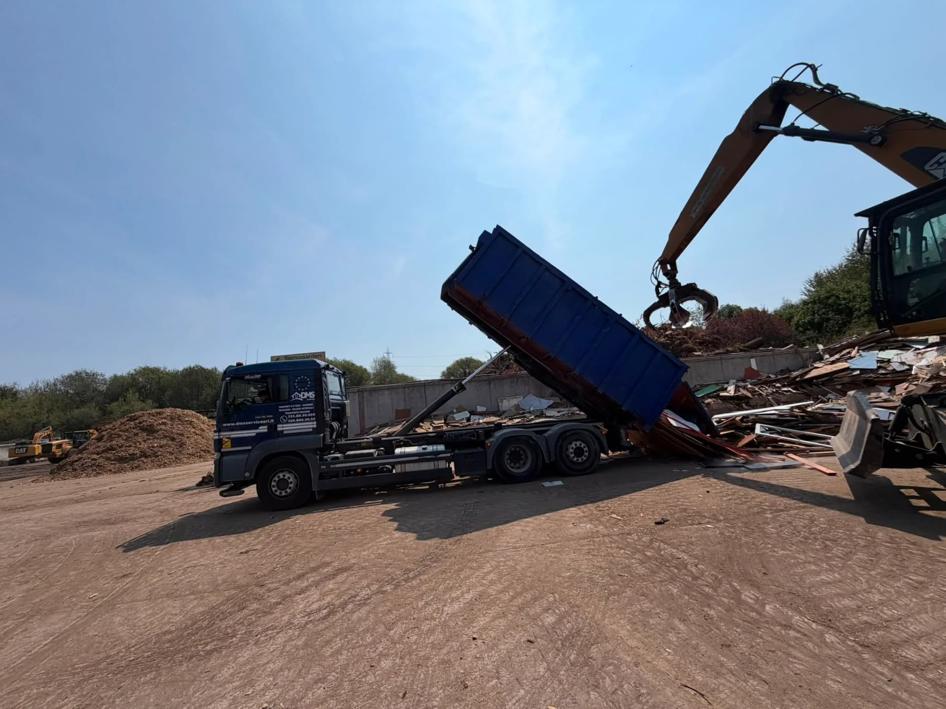 Camion DMS Service in scarico rifiuti con escavatore